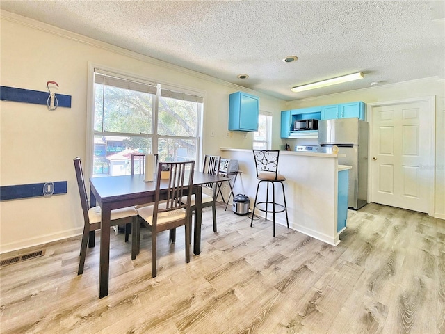 dining room with visible vents, a textured ceiling, light wood-style flooring, and crown molding