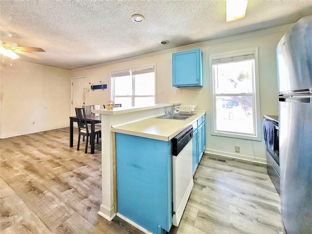 kitchen featuring blue cabinetry, light wood-style flooring, freestanding refrigerator, a sink, and dishwasher