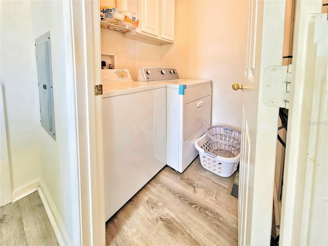 laundry room with baseboards, light wood-style flooring, electric panel, separate washer and dryer, and cabinet space