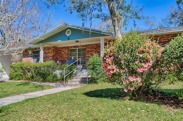 single story home with brick siding, a porch, and a front yard