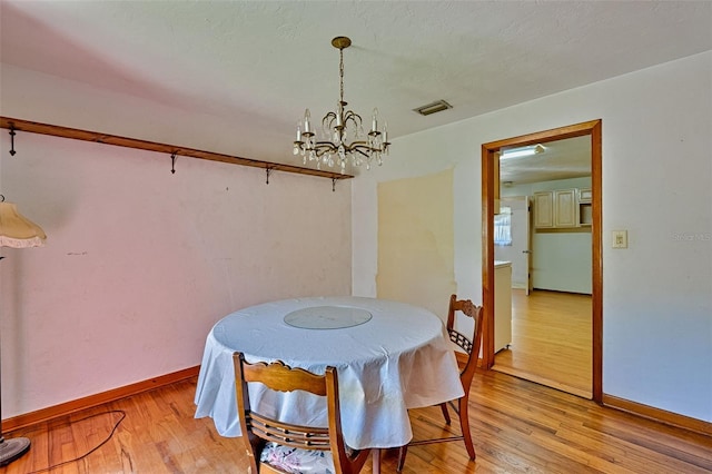 dining area with visible vents, baseboards, a notable chandelier, and light wood-style flooring