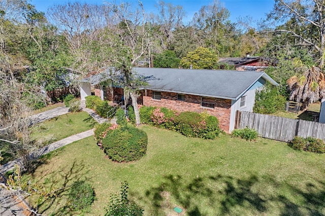 exterior space with brick siding, a front yard, and fence