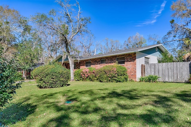 exterior space with brick siding, a front lawn, and fence