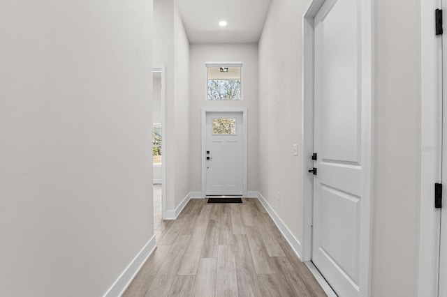 entryway with baseboards, a high ceiling, and light wood-style floors