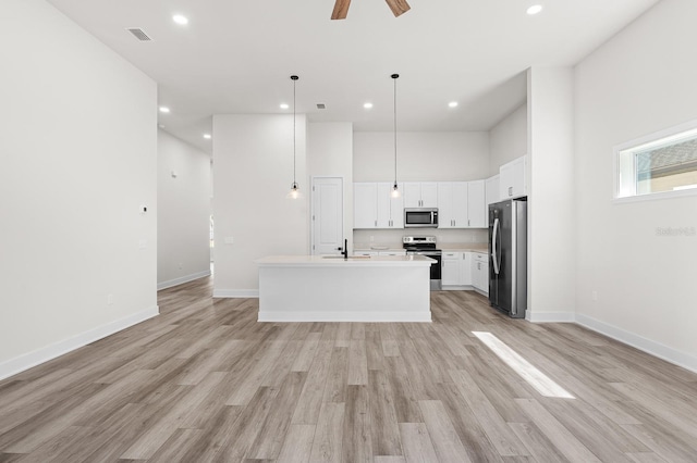 kitchen featuring visible vents, a sink, stainless steel appliances, light wood-style floors, and light countertops