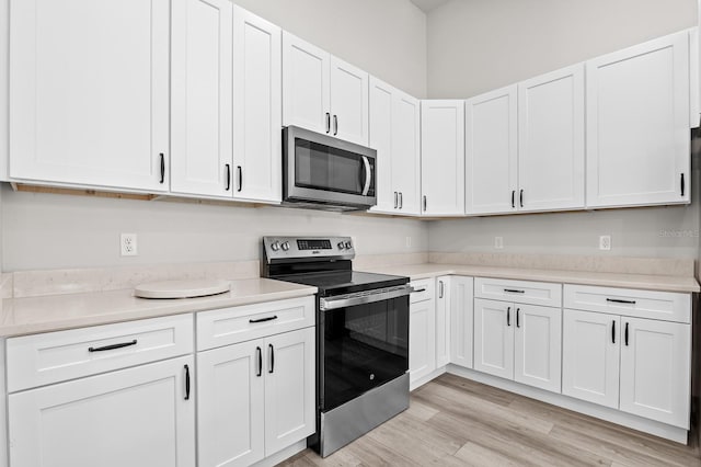 kitchen featuring light wood-type flooring, stainless steel appliances, white cabinets, and light countertops