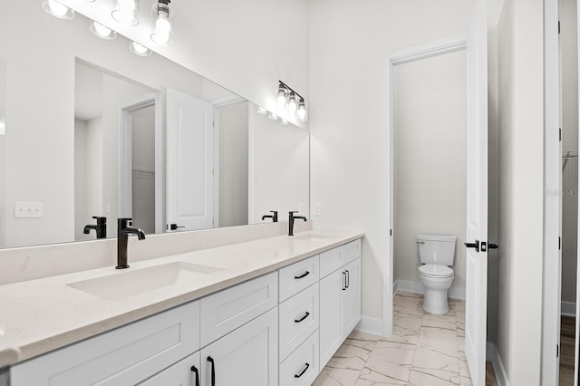 bathroom featuring double vanity, marble finish floor, toilet, and a sink