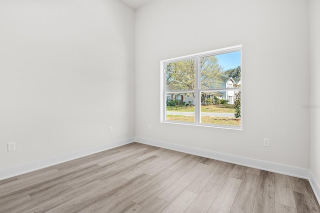 spare room featuring baseboards and light wood finished floors