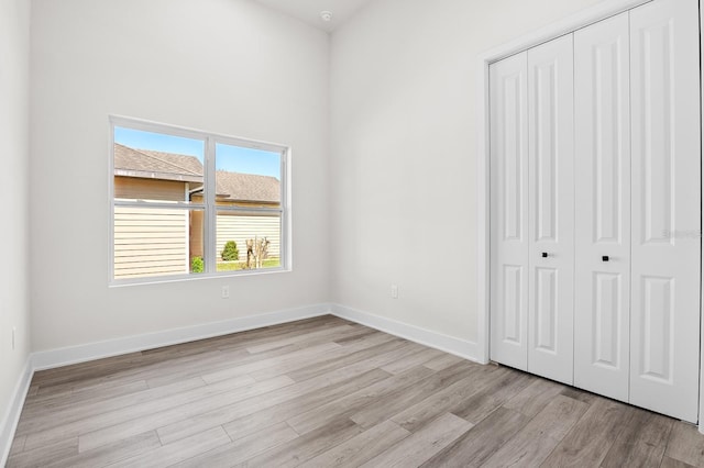 unfurnished bedroom with a closet, light wood-type flooring, and baseboards