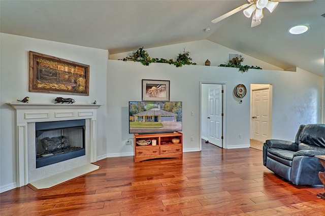 living area with lofted ceiling, a fireplace with flush hearth, wood finished floors, and ceiling fan