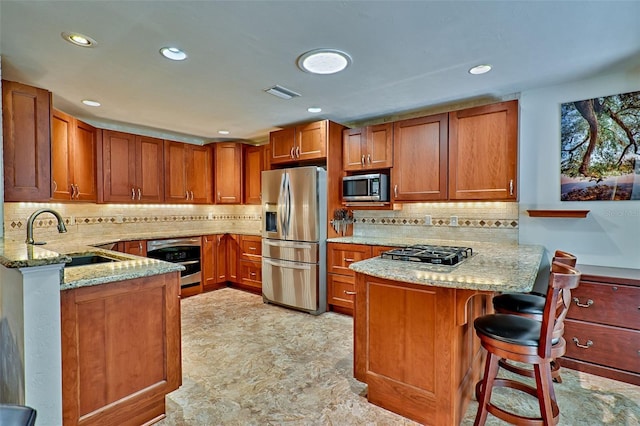 kitchen featuring visible vents, a peninsula, a sink, appliances with stainless steel finishes, and brown cabinets