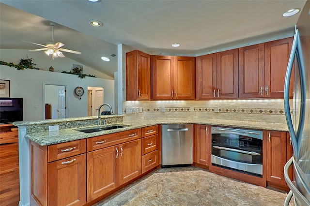 kitchen with light stone countertops, brown cabinets, a peninsula, stainless steel appliances, and a sink