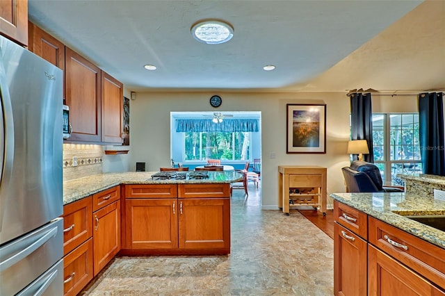 kitchen featuring a healthy amount of sunlight, a peninsula, stainless steel appliances, and brown cabinets