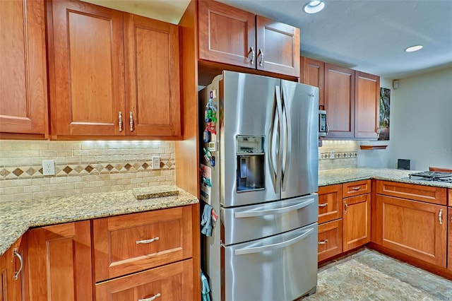 kitchen featuring tasteful backsplash, recessed lighting, stainless steel fridge, brown cabinetry, and light stone countertops