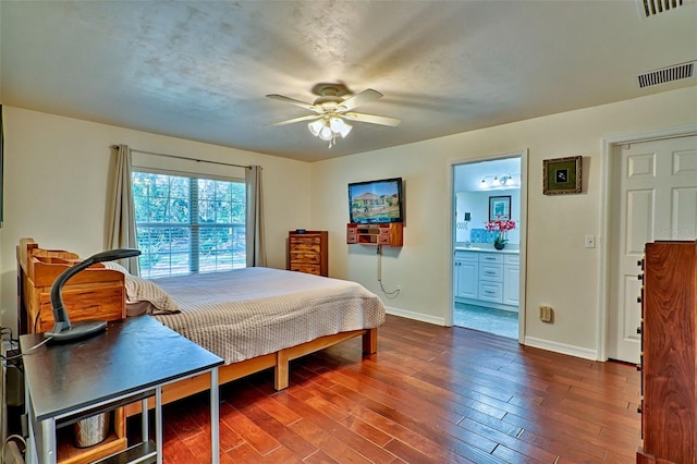 bedroom with visible vents, dark wood-type flooring, a ceiling fan, ensuite bath, and baseboards