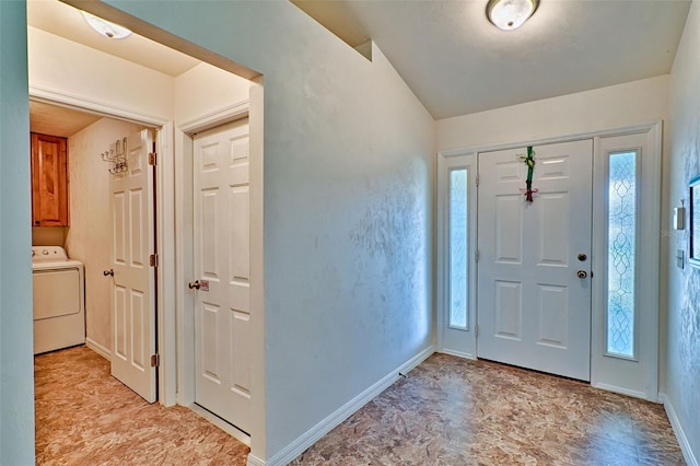 foyer entrance with baseboards, washer / clothes dryer, lofted ceiling, and stone finish flooring