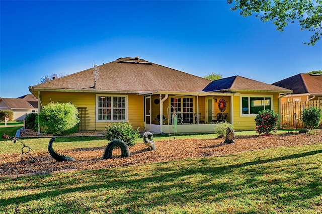 rear view of house with a yard, fence, a sunroom, and roof with shingles