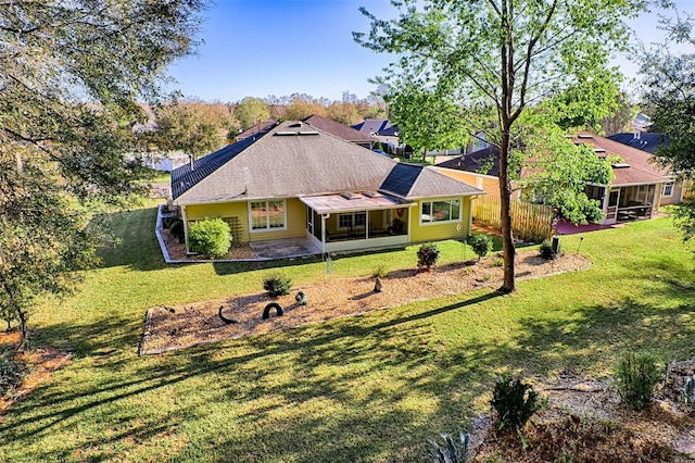 exterior space with a patio area, a lawn, a sunroom, and a shingled roof