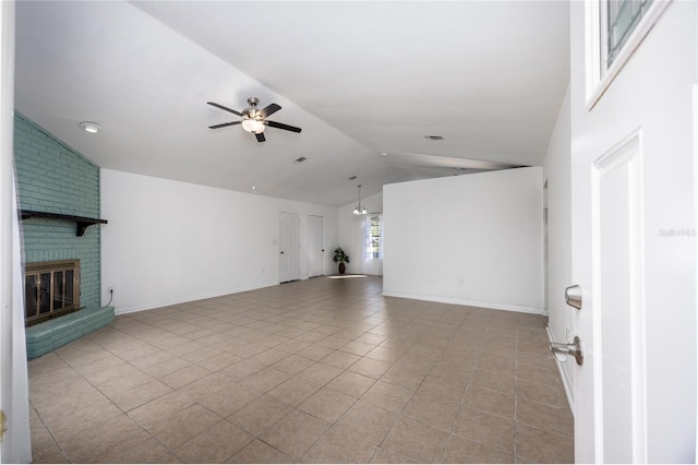 unfurnished living room with a brick fireplace, baseboards, vaulted ceiling, light tile patterned flooring, and a ceiling fan