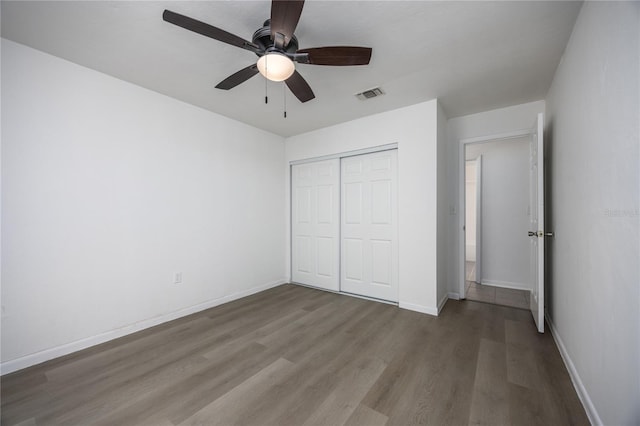 unfurnished bedroom with a ceiling fan, wood finished floors, visible vents, baseboards, and a closet