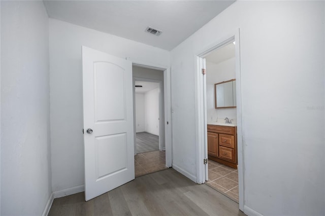 unfurnished bedroom featuring a sink, visible vents, baseboards, and light wood-style floors