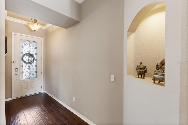 foyer entrance featuring arched walkways, crown molding, baseboards, and dark wood-style flooring