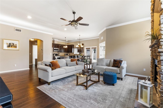 living area with visible vents, dark wood-type flooring, baseboards, ceiling fan with notable chandelier, and arched walkways