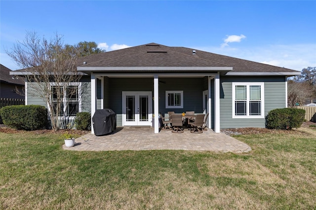 rear view of house with french doors, a lawn, roof with shingles, and a patio area