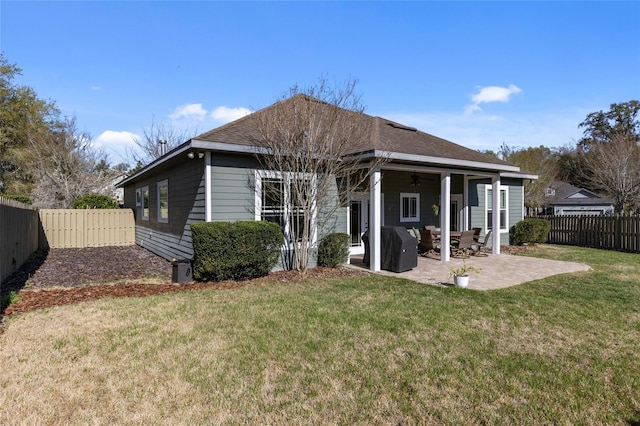 back of property with a patio area, a yard, a shingled roof, and a fenced backyard