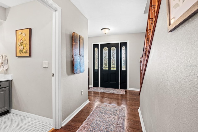 foyer with stairway, baseboards, and wood finished floors