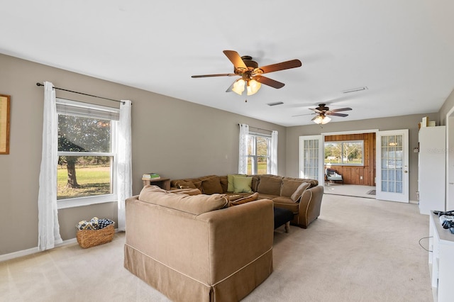 living room featuring ceiling fan, light colored carpet, visible vents, and baseboards