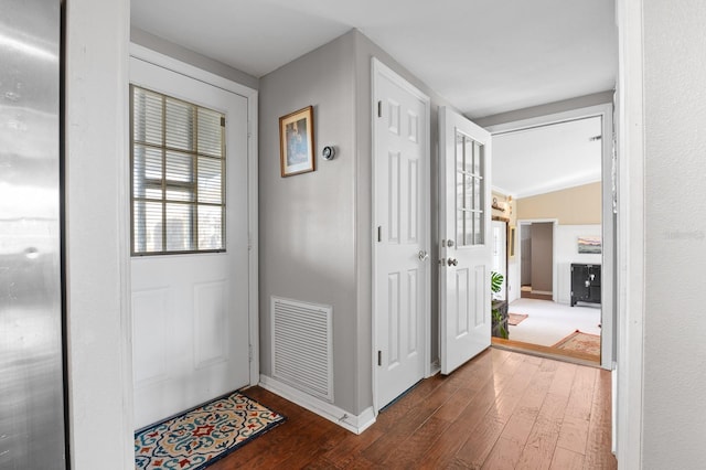 interior space featuring dark wood-style floors, visible vents, baseboards, and lofted ceiling