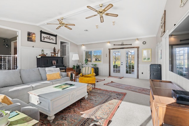 carpeted living room featuring french doors, lofted ceiling, a wainscoted wall, and crown molding