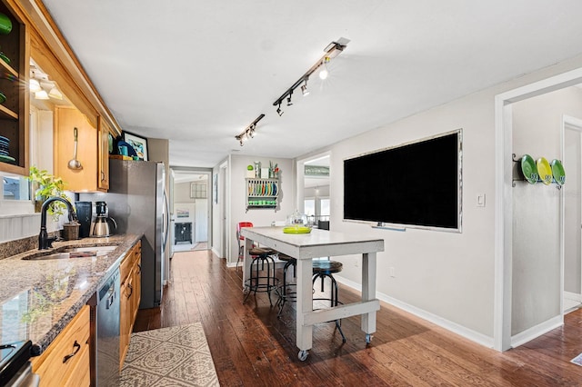 kitchen with baseboards, light stone countertops, dark wood finished floors, appliances with stainless steel finishes, and a sink