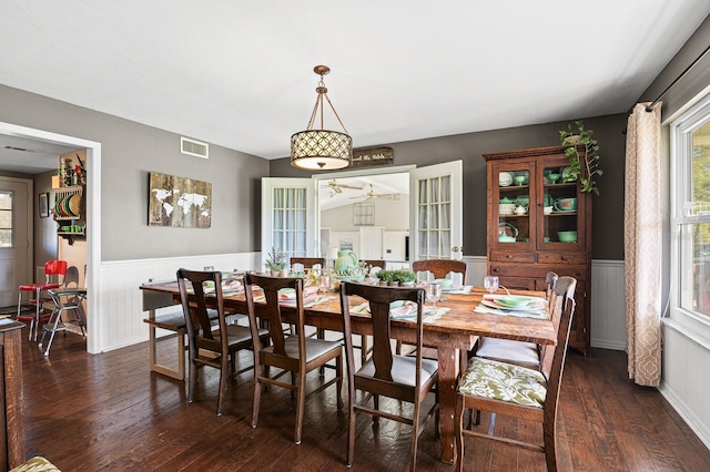 dining room with dark wood finished floors, visible vents, and wainscoting