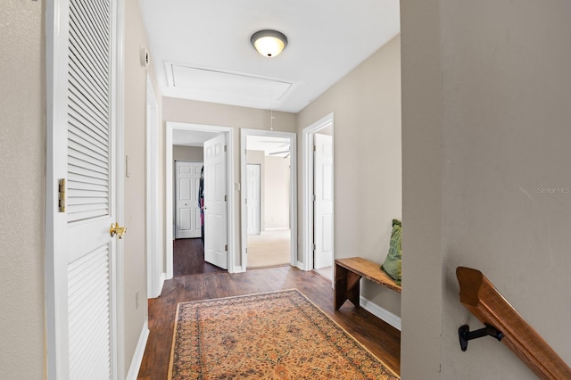 corridor featuring attic access, wood finished floors, and baseboards