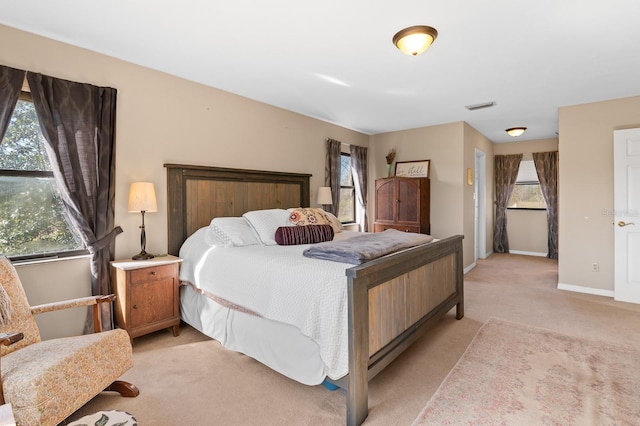 bedroom with baseboards, visible vents, and light carpet