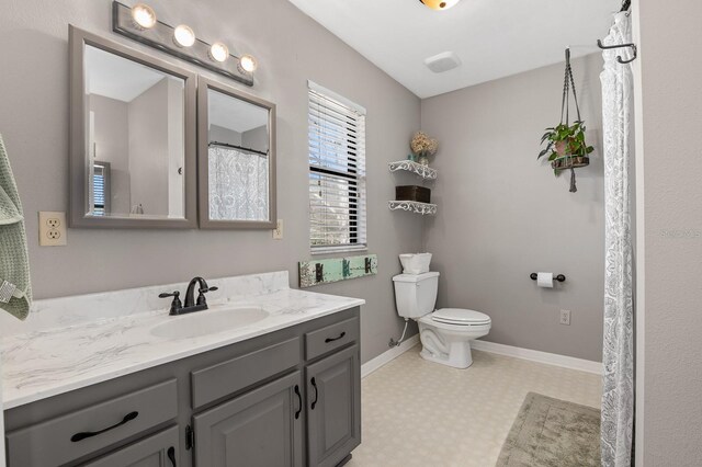 bathroom featuring vanity, tile patterned floors, toilet, and baseboards