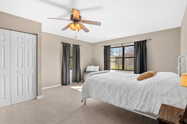 carpeted bedroom with a ceiling fan, baseboards, and a closet