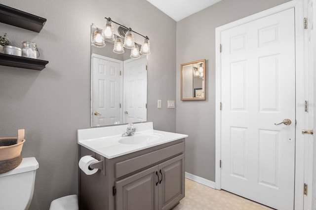 half bath featuring tile patterned floors, baseboards, toilet, and vanity