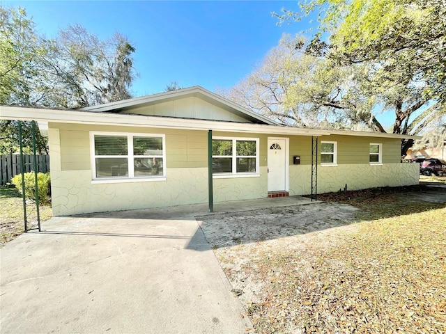 single story home with concrete block siding and fence