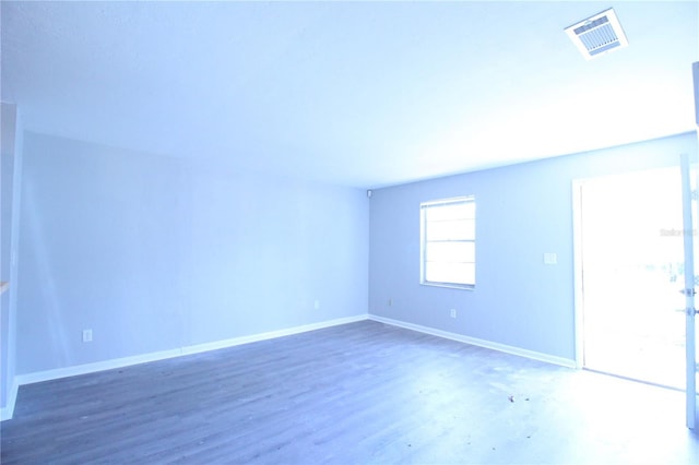 empty room with wood finished floors, baseboards, and visible vents