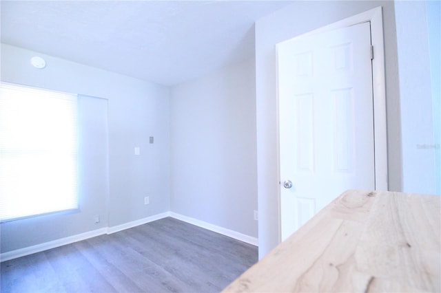 unfurnished bedroom with baseboards and dark wood-type flooring