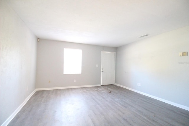 empty room featuring visible vents, baseboards, and wood finished floors