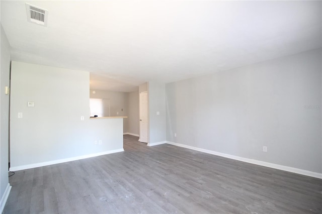 unfurnished living room with visible vents, baseboards, and dark wood-type flooring