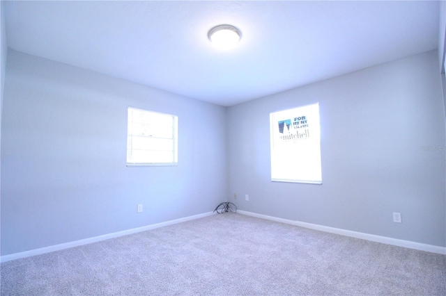 carpeted spare room featuring plenty of natural light and baseboards