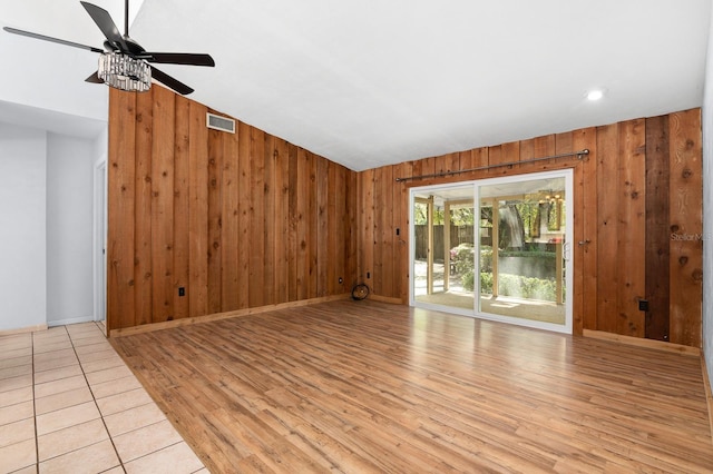 unfurnished living room featuring baseboards, visible vents, light wood finished floors, and wood walls