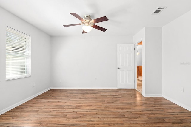 spare room featuring visible vents, a ceiling fan, baseboards, and wood finished floors