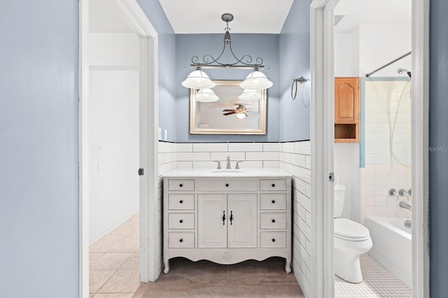 full bath featuring toilet, tile walls, tile patterned flooring, tub / shower combination, and vanity