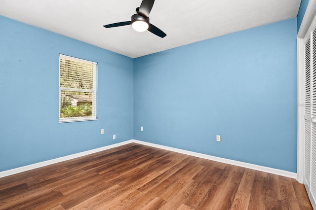 unfurnished bedroom with a closet, baseboards, dark wood-type flooring, and ceiling fan